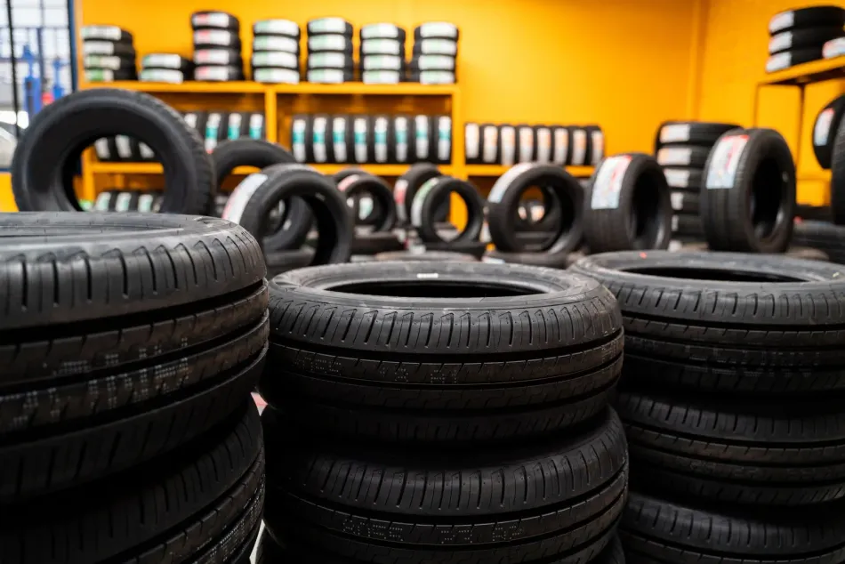 Tire shop exterior: Tires stacked outside a yellow building. A truck is visible on the left.