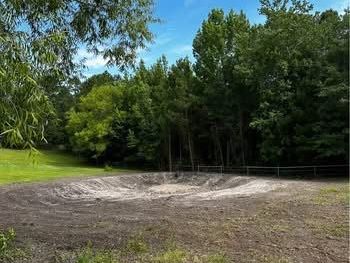 There is a large hole in the middle of a field surrounded by trees.