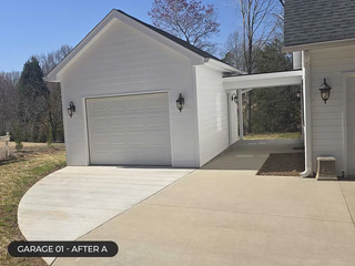 White detached garage with a concrete driveway and breezeway beside a house under a clear sky