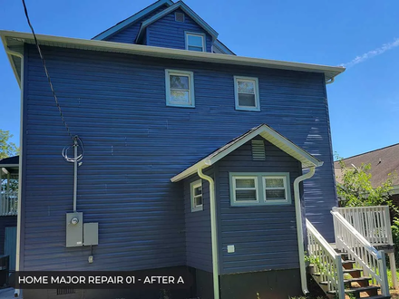 Blue two-story house with small porch and side staircase under a clear sky