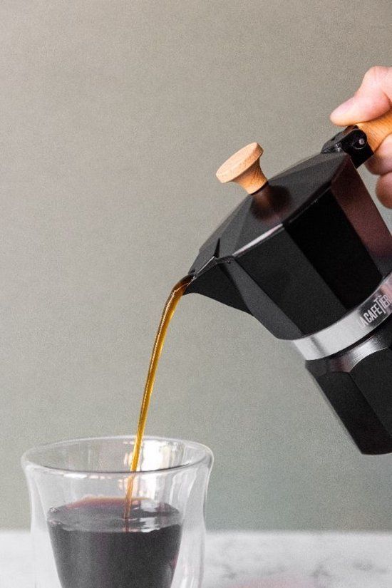 Een koffiepot en een kopje koffie staan ​​op een rots.