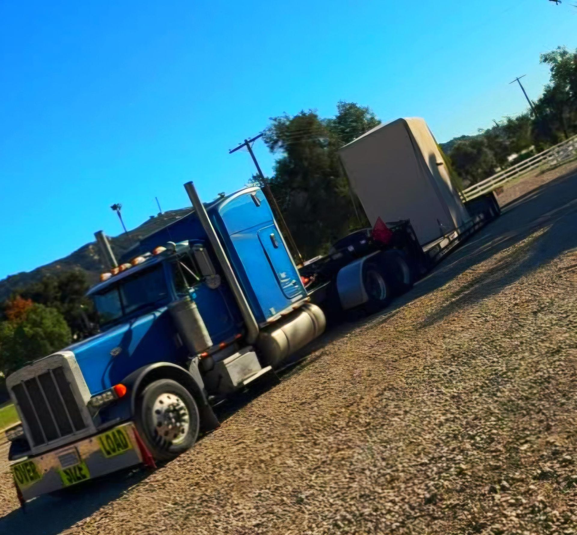 Truck trailer loaded with bundled pipes and wooden crates, under blue sky.