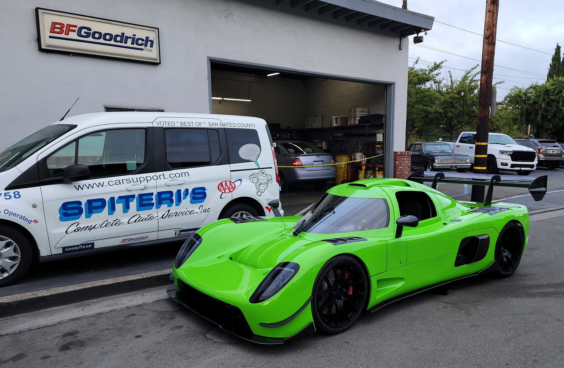 Bright green sports car parked in front of a tire shop with a white van. | Spiteri's Auto Service