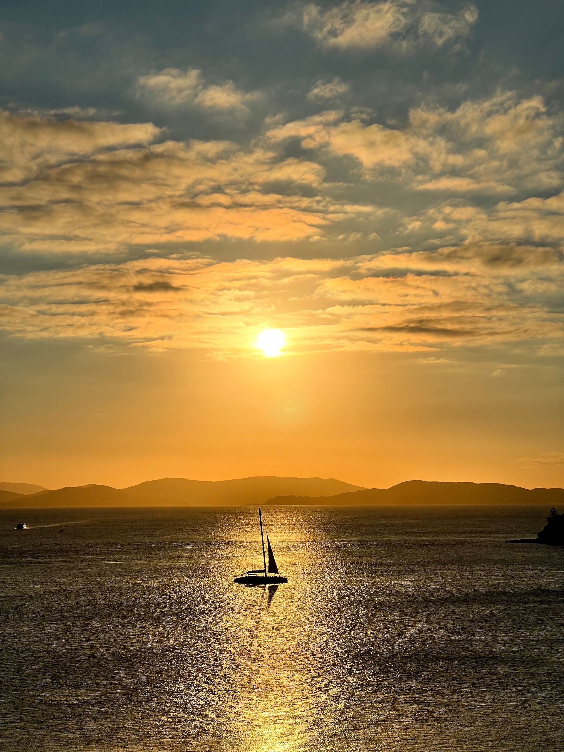 A boat is floating on top of a body of water at sunset.