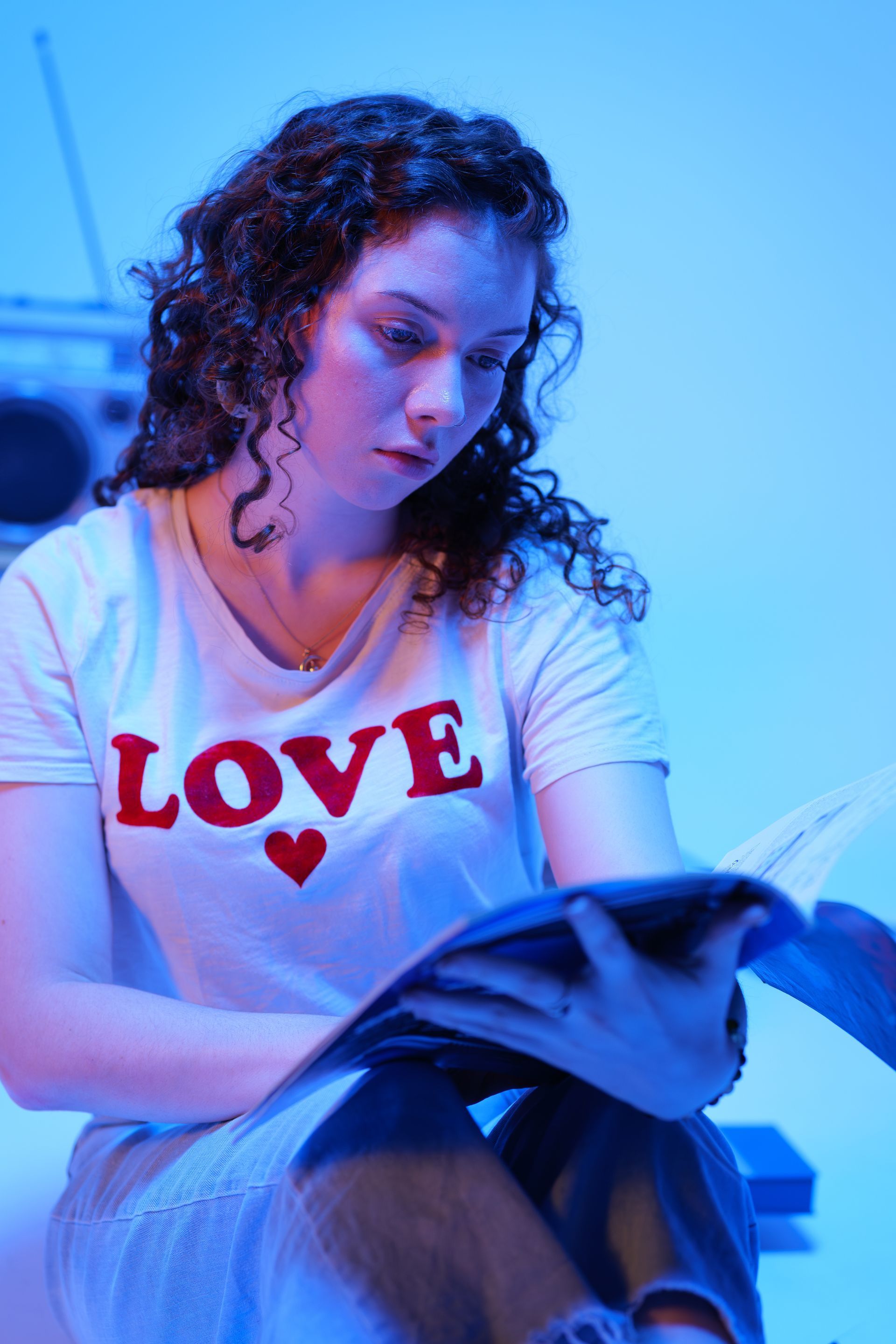 A person with curly hair wearing a white shirt with 