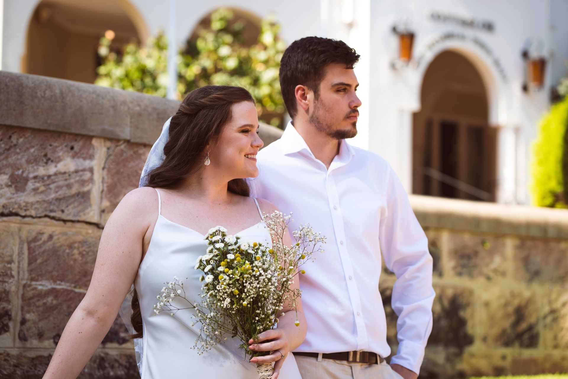 A bride and groom are posing for a picture in front of a building.