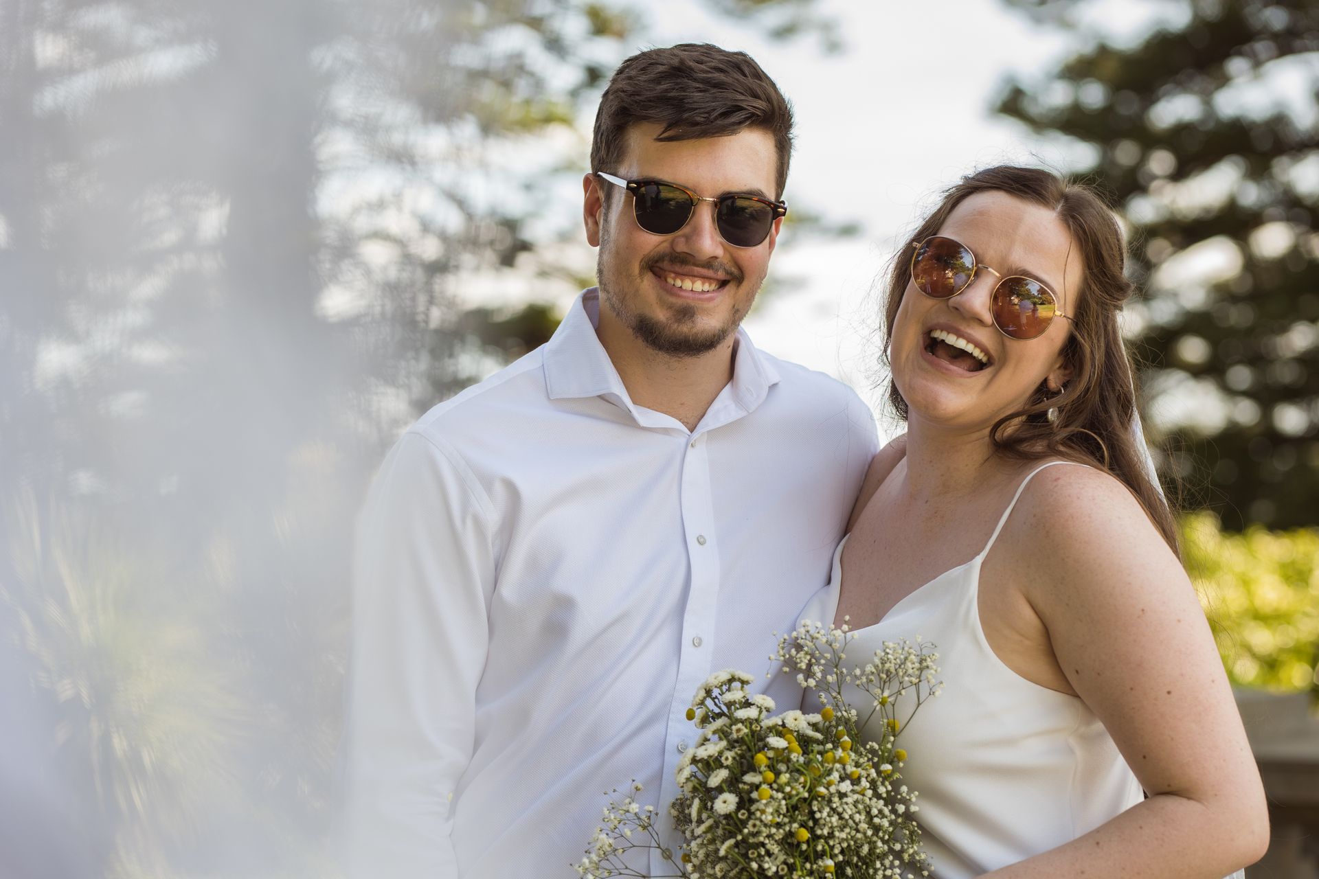 A bride and groom are posing for a picture in a park.