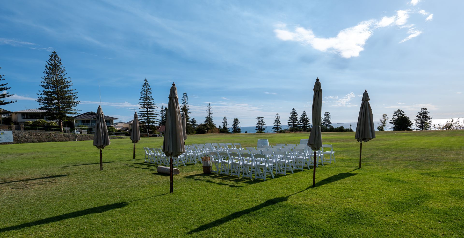 A field filled with chairs and umbrellas for a wedding ceremony.