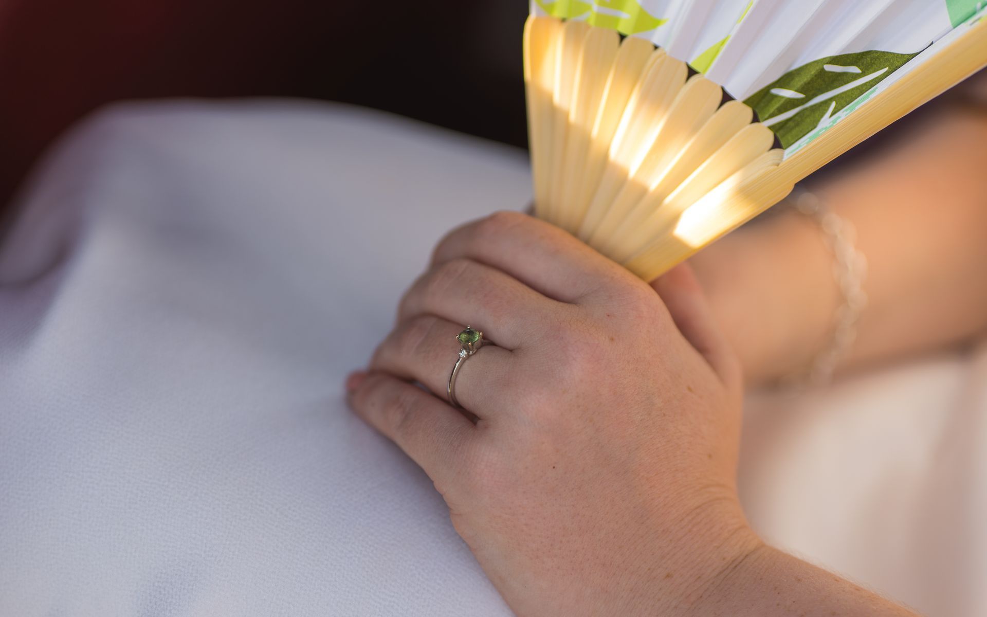 A bride with a ring on her finger is holding a fan.