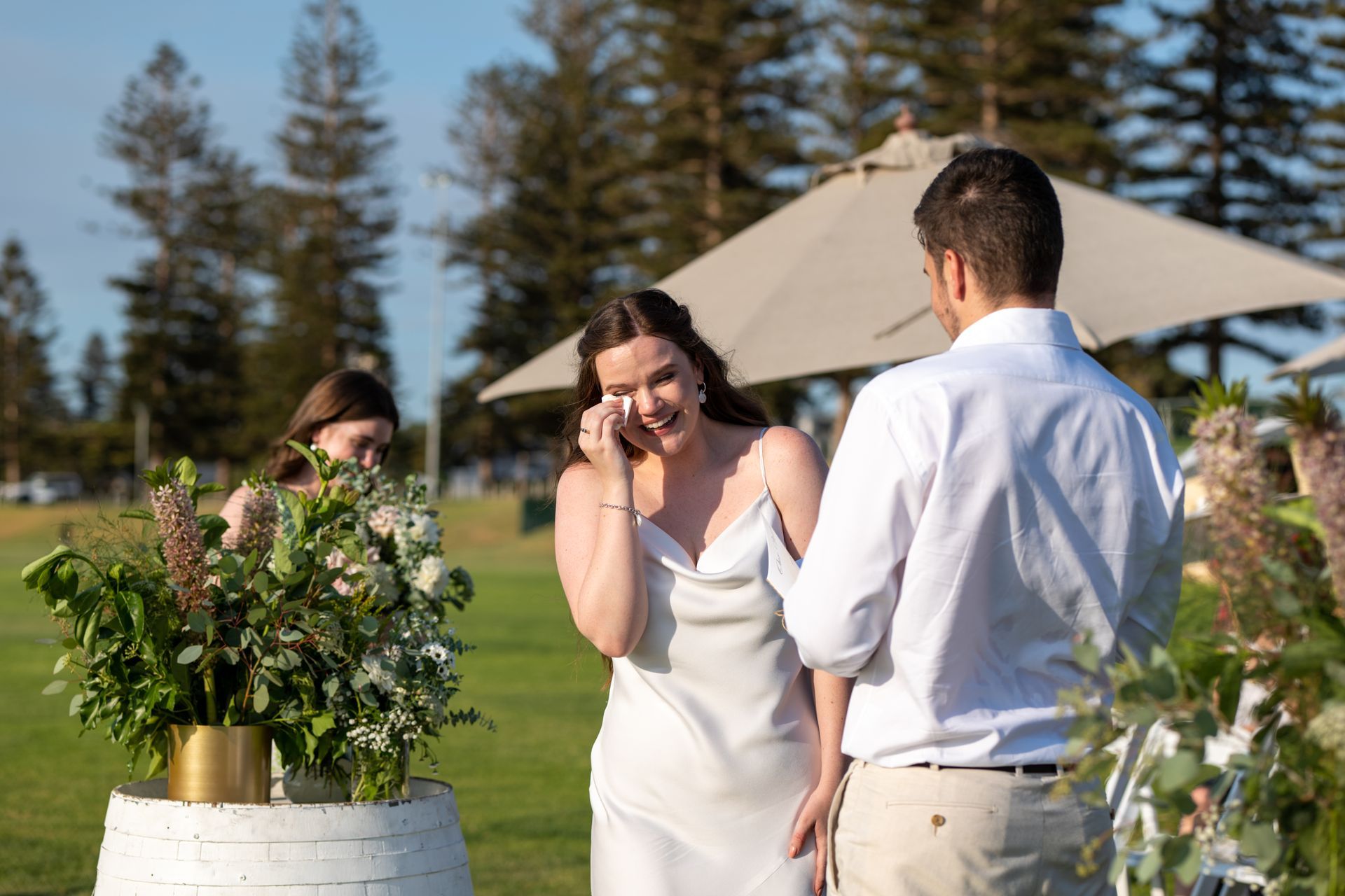 A bride and groom are getting married in a field and the bride is crying.