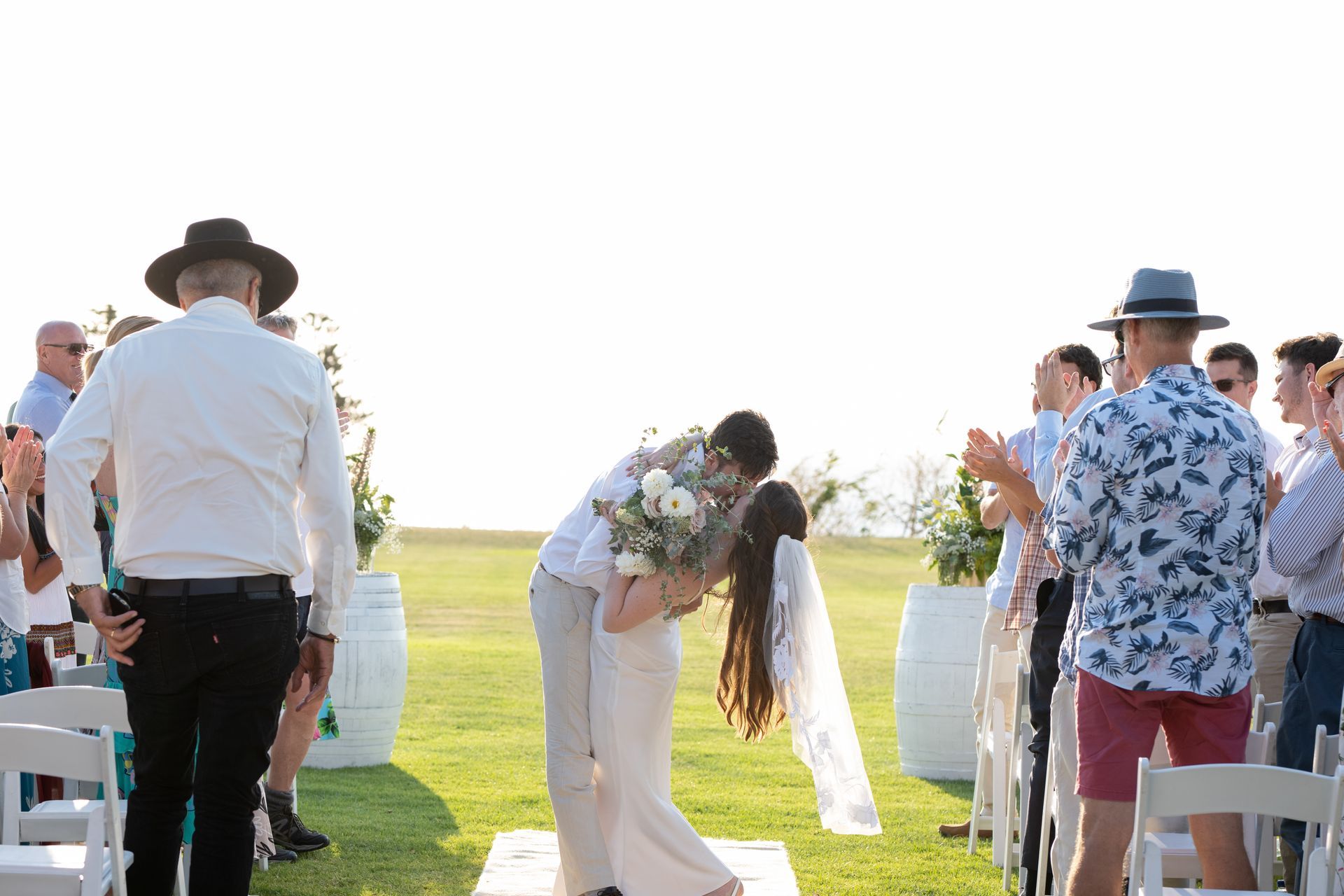 A bride and groom are kissing at their wedding ceremony.