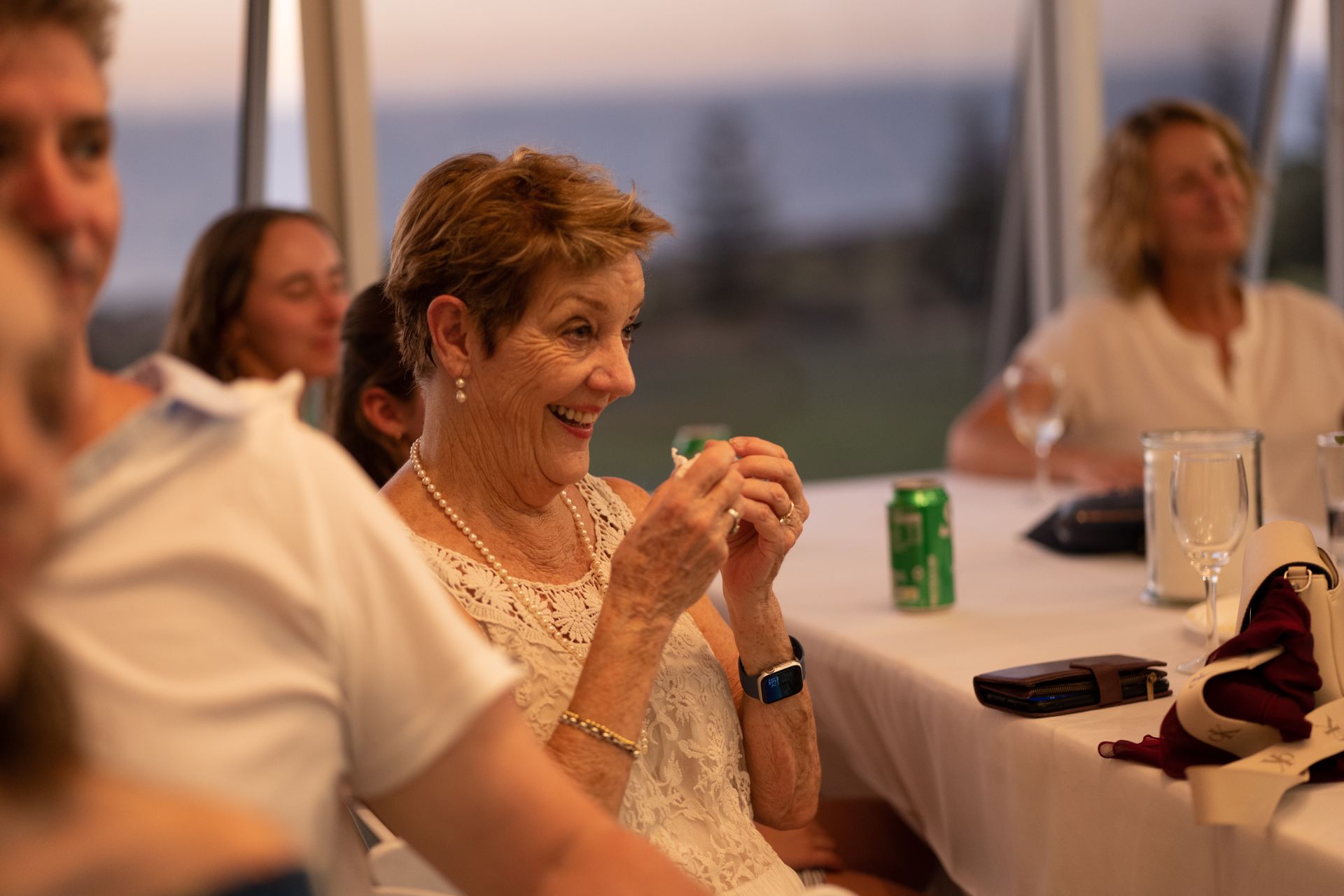 A woman is sitting at a table with a smile on her face.