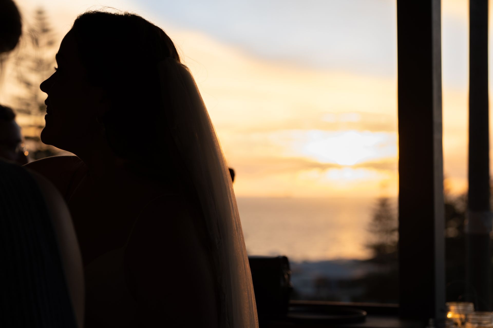 A silhouette of a bride and groom looking out a window at sunset.
