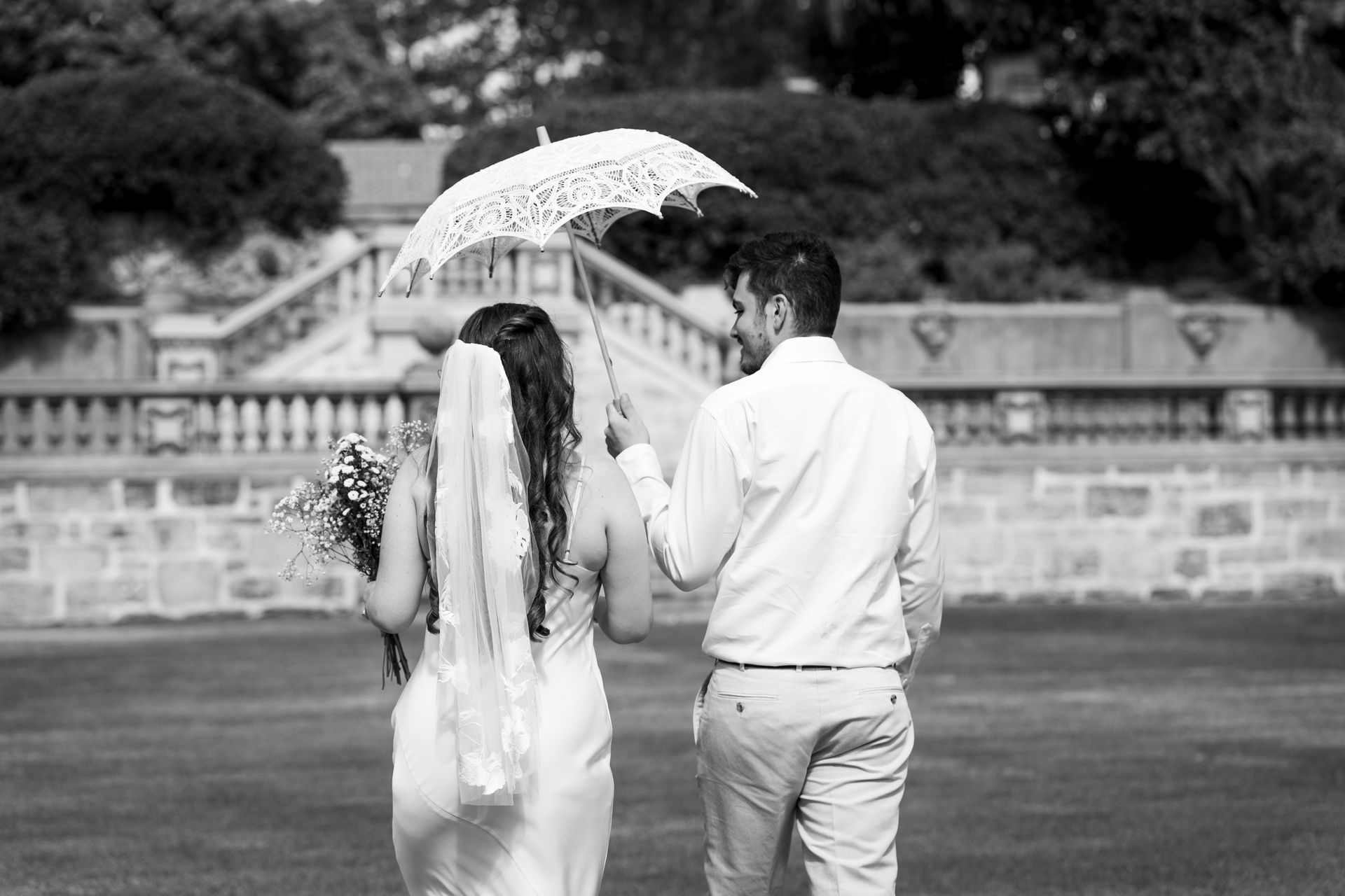 A married couple walking away with a parasol.