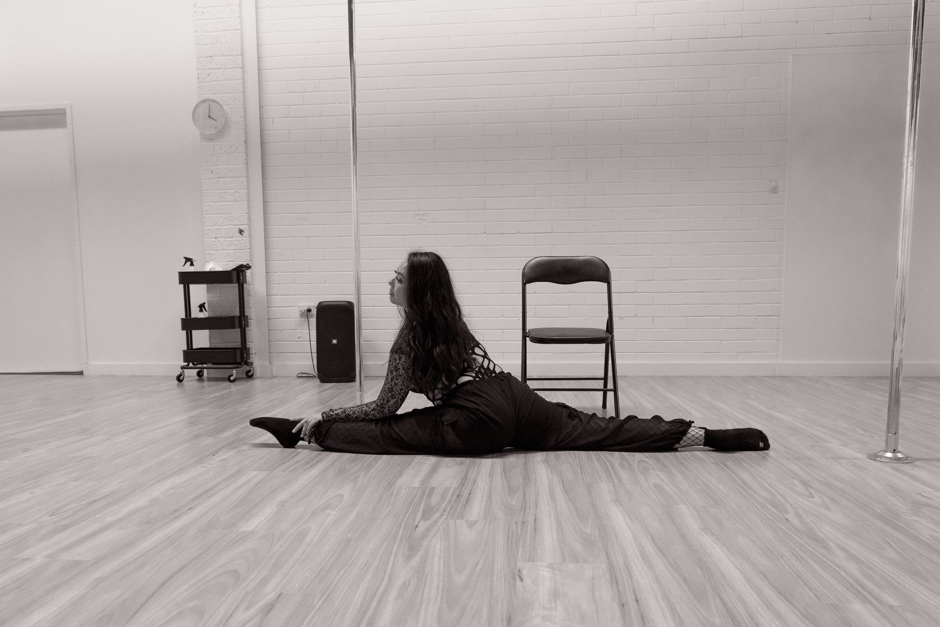 A woman is doing a split on the floor in a dance studio.