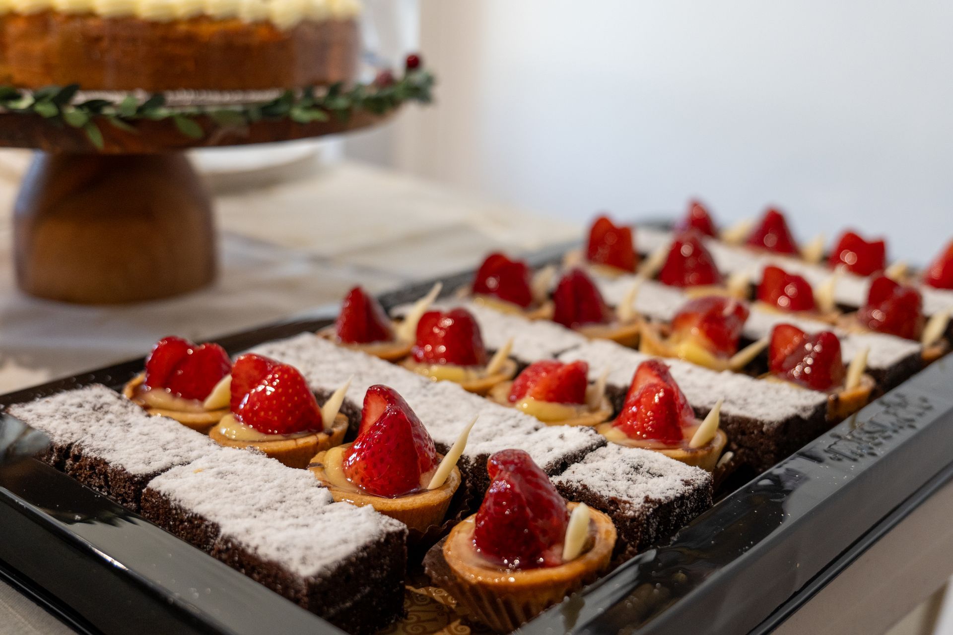 A tray of desserts with strawberries on top of them on a table.
