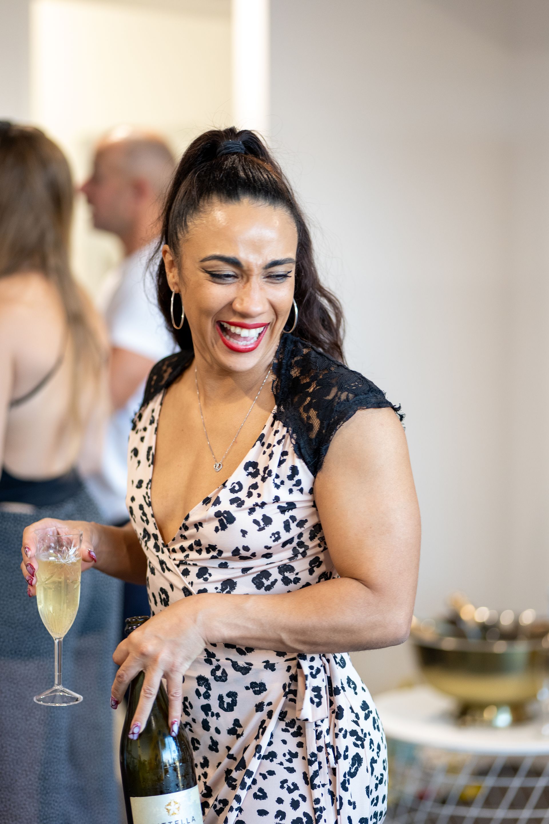 A woman is holding a glass of champagne and a bottle of champagne.