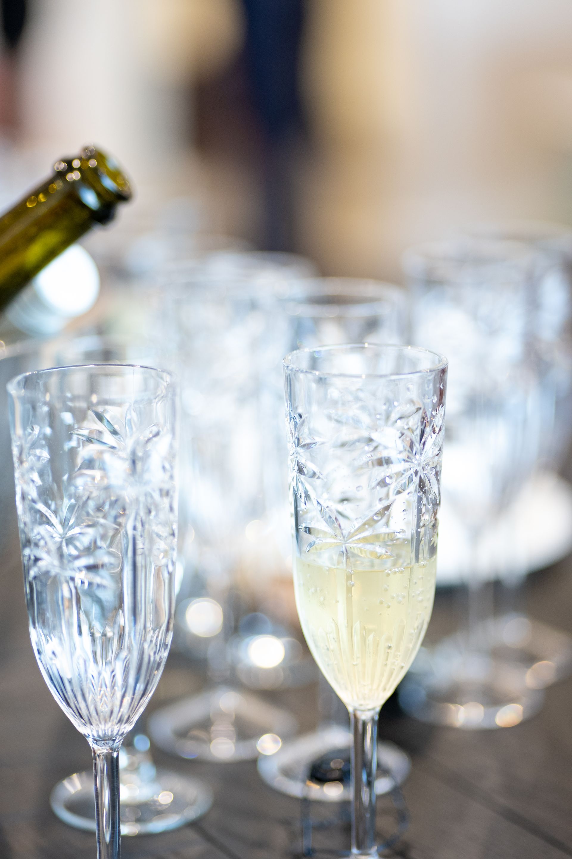 A bottle of champagne is being poured into a glass on a table
