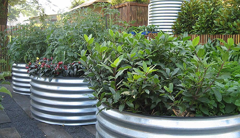 A Row of Metal Planters Filled with Plants in A Garden — Maitland Sheet Metal in Rutherford, NSW