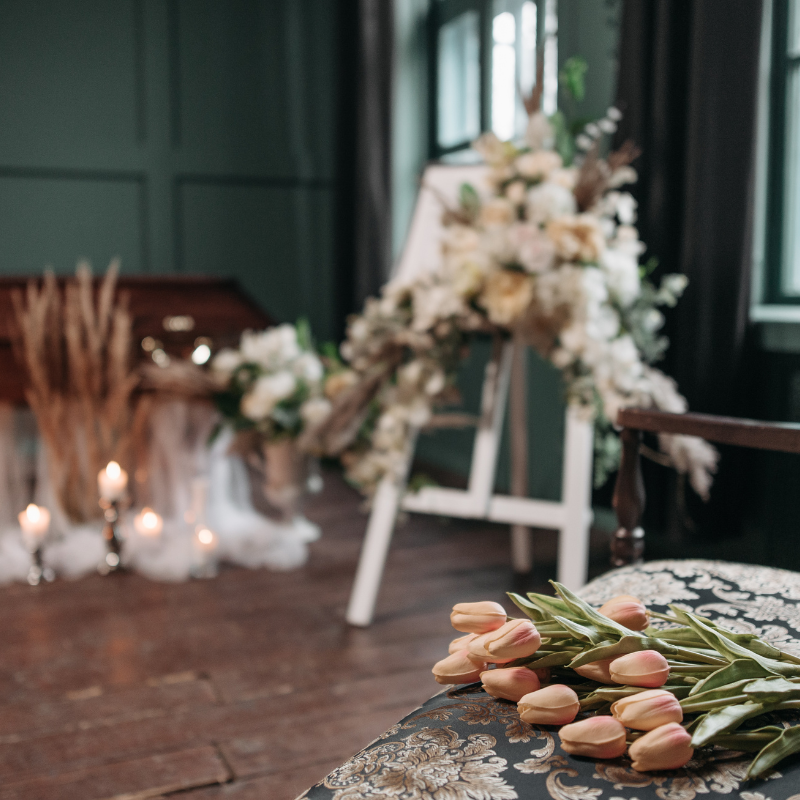 Floral wedding arch with candles and pale bouquets in a dark green room, with tulips on the floor