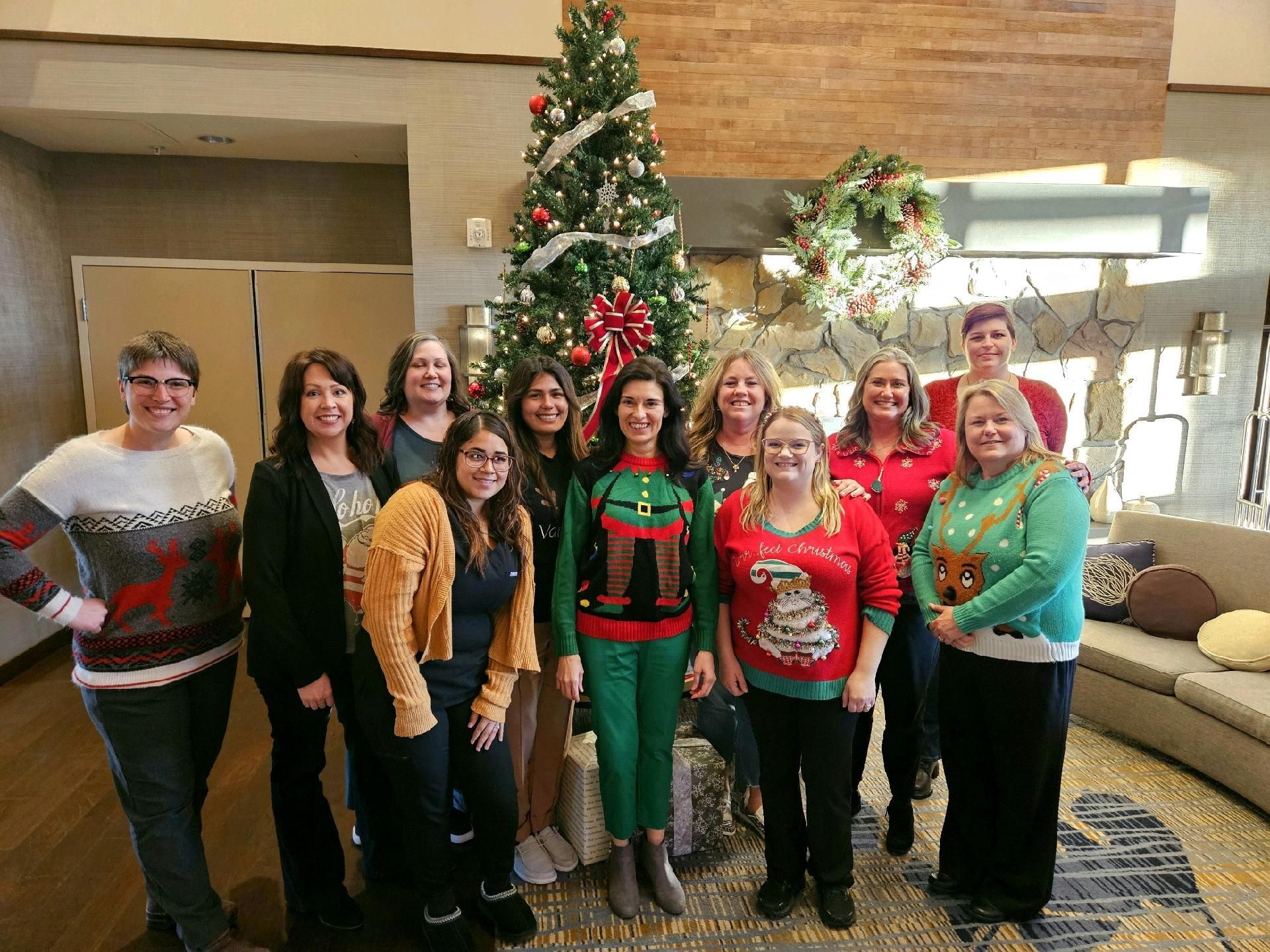 A group of women are posing for a picture in front of a christmas tree.