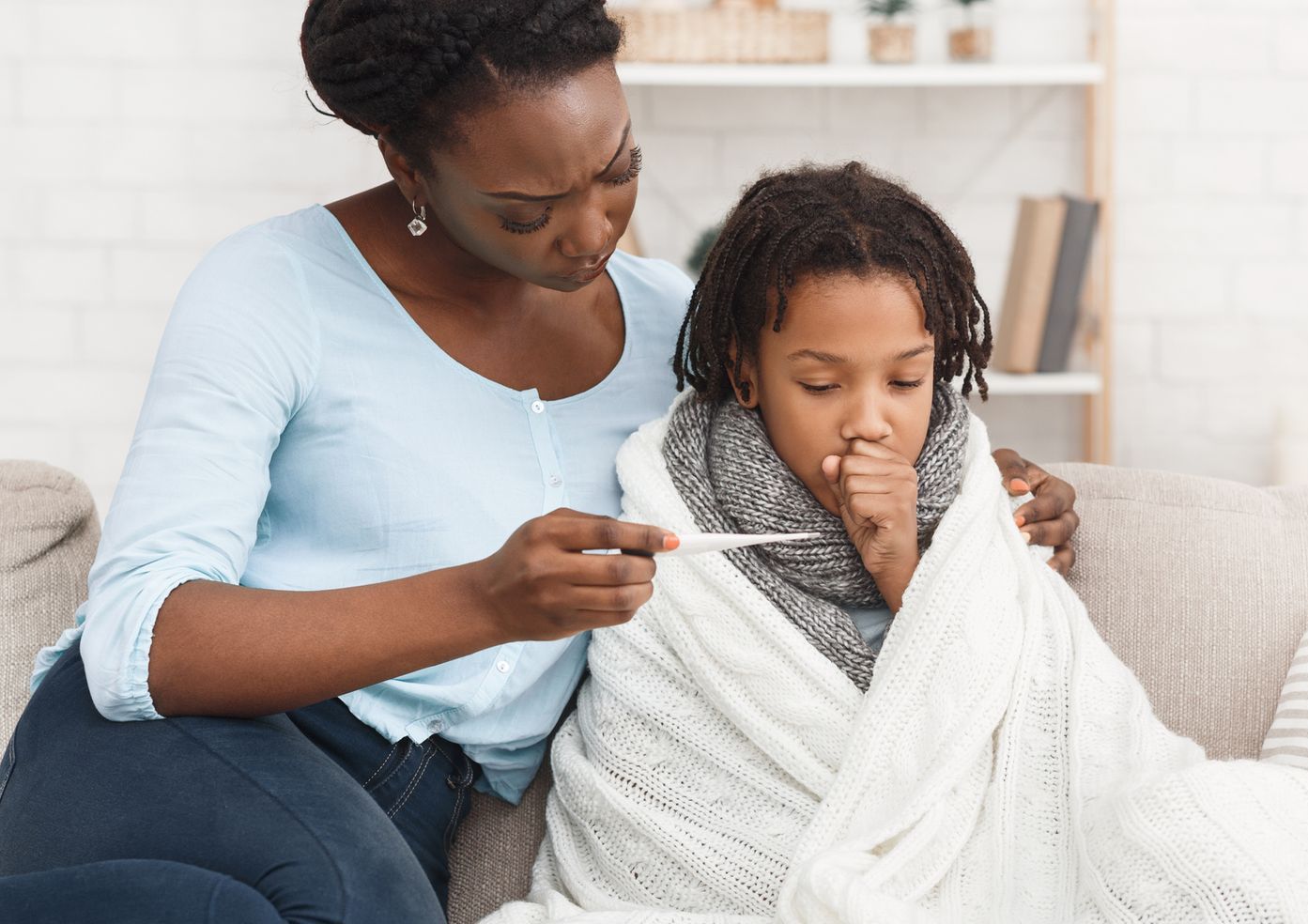 a woman is taking a child 's temperature on a couch 