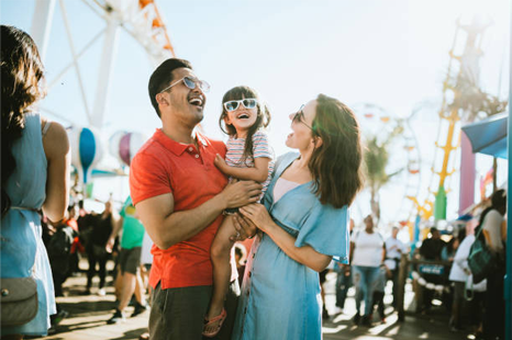 a man and woman are holding a little girl at a carnival