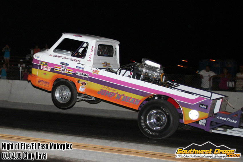 A tow truck is being towed by a motorcycle on a race track.