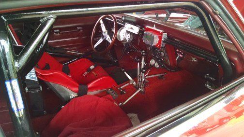 The inside of a race car with red seats and a steering wheel