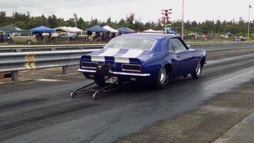 A blue car is pulling a trailer on a race track