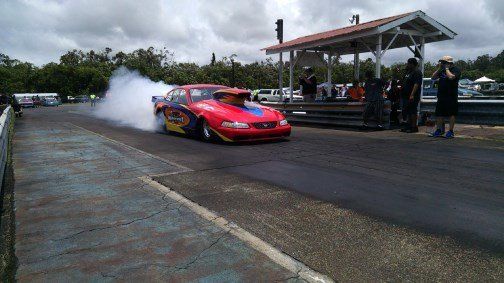 A red car is doing a burnout on a race track