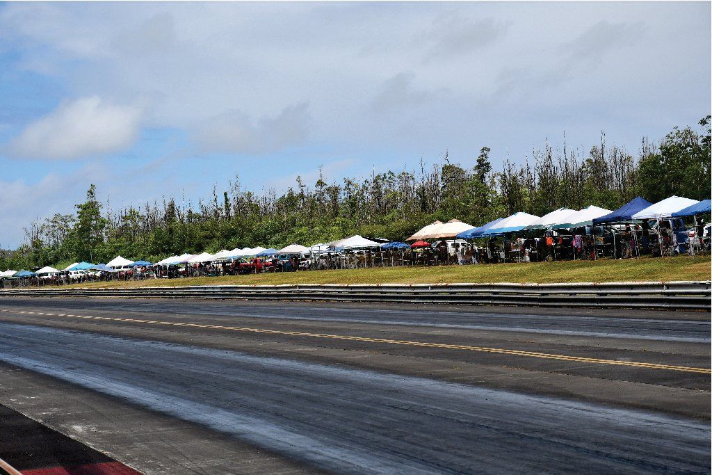 A row of tents are lined up on the side of a road.