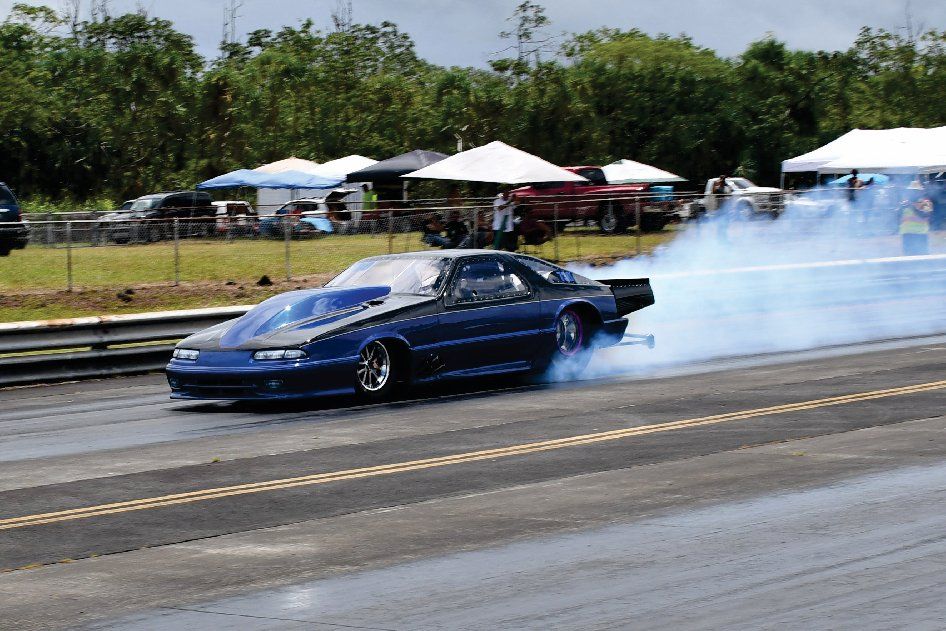 A blue car is doing a burnout on a race track