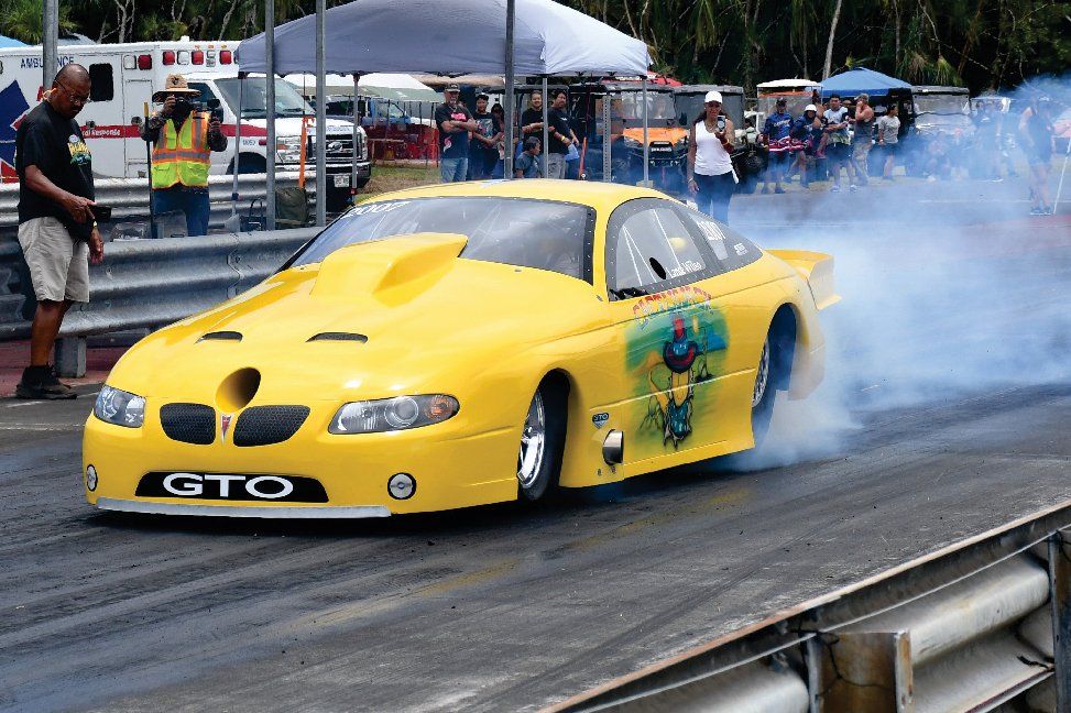 A yellow gto race car is doing a burnout on a track