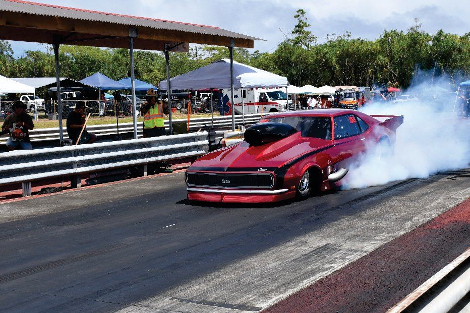 A red car is doing a burnout on a race track