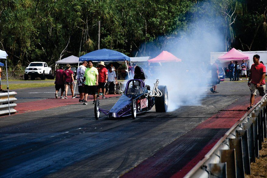 A person is driving a drag race car on a track.