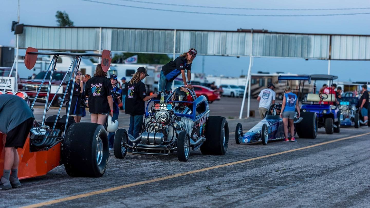 A group of people are working on a race car on a track.