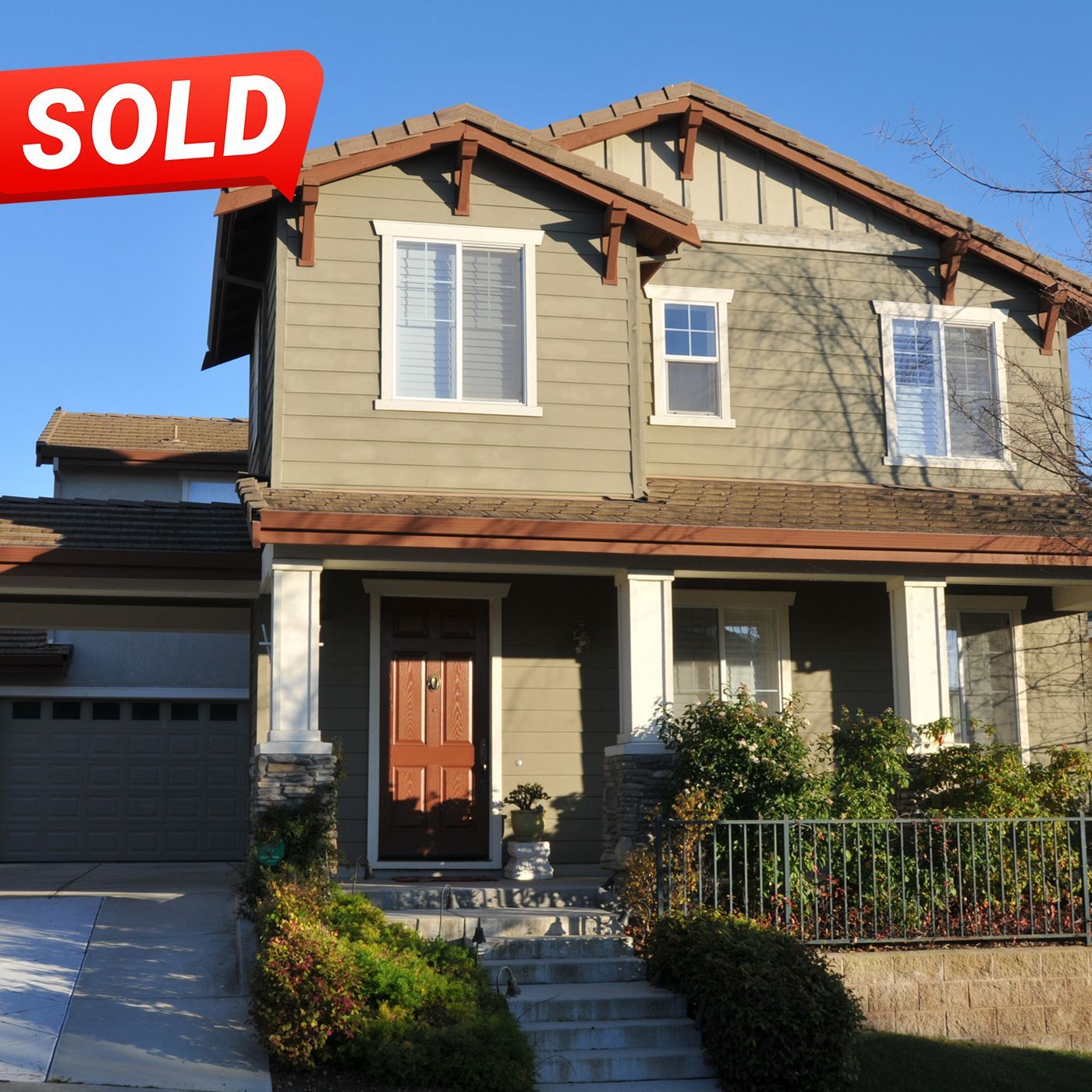 A brown house with a sold sign above it