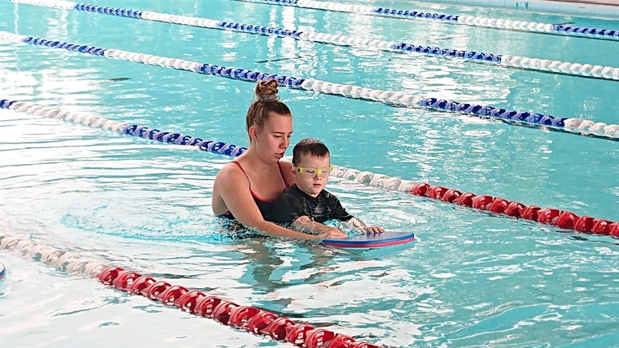 Woman Guiding The Child In Pool — Swim Training In Cannonvale, QLD