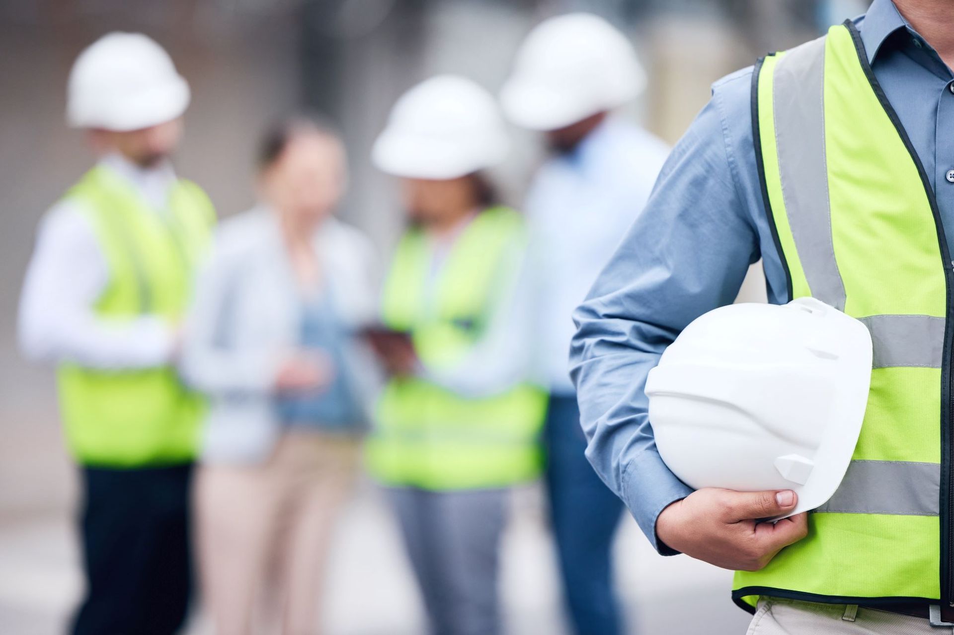 A man is holding a hard hat in front of a group of construction workers.