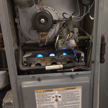 Open furnace with blue flames in burners; blower fan and gas valve visible.