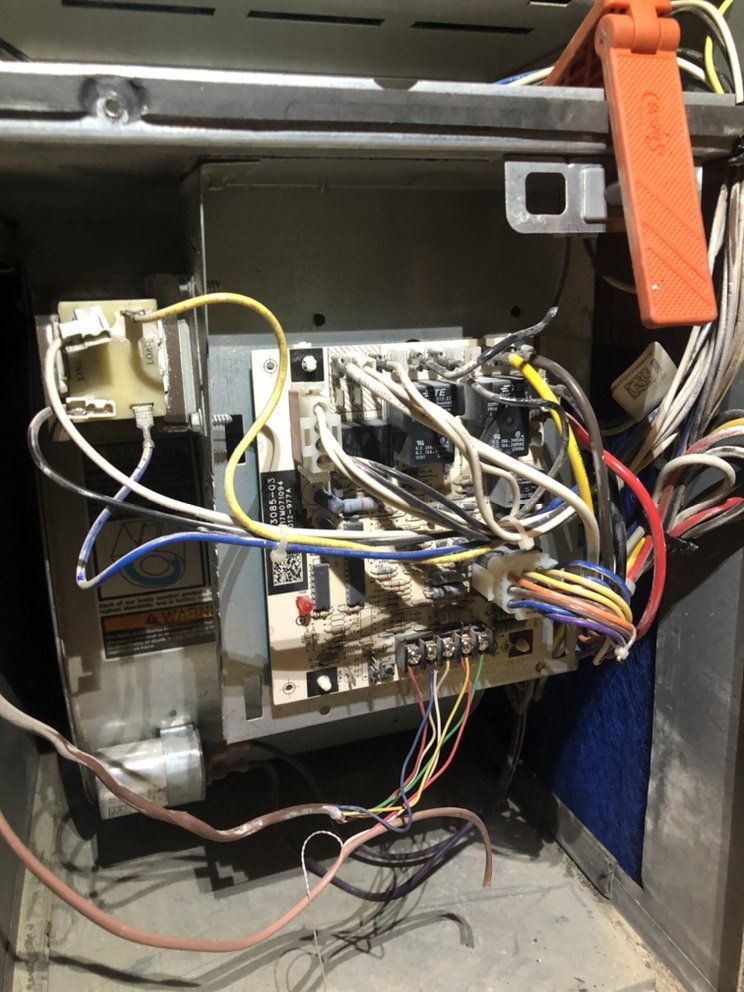 Furnace control panel with wires and circuit board visible. Wires are various colors.
