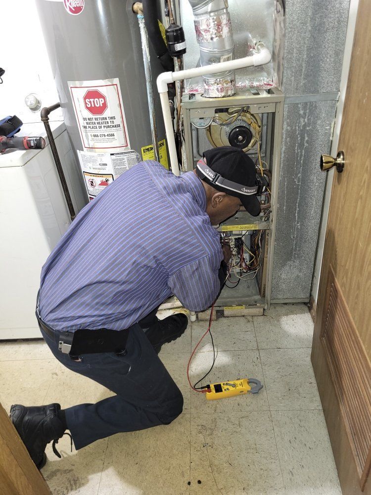 HVAC technician kneeling, inspecting furnace with multimeter in a utility room.