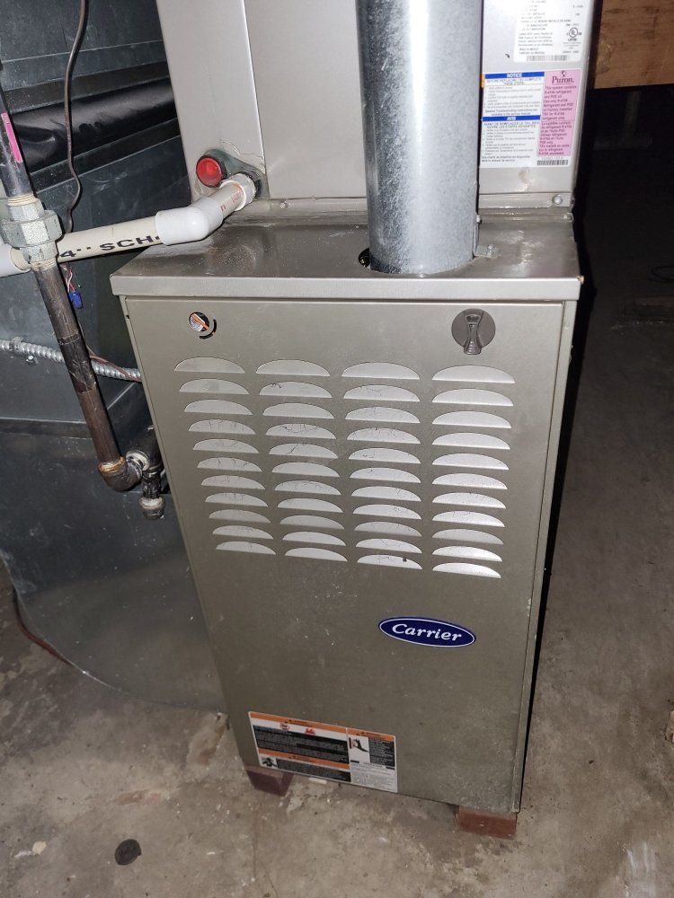 A silver Carrier furnace with a vent, in a basement setting.