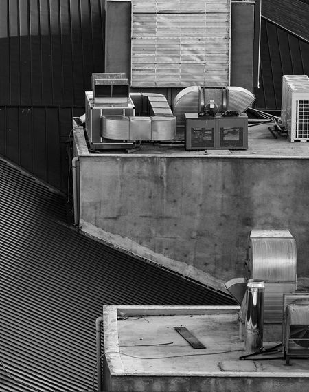 Black and white photo of a building rooftop with HVAC units, vents, and various equipment.