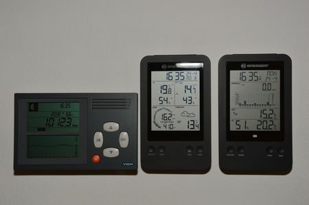 Three black digital weather stations side-by-side, displaying various atmospheric readings and graphs.
