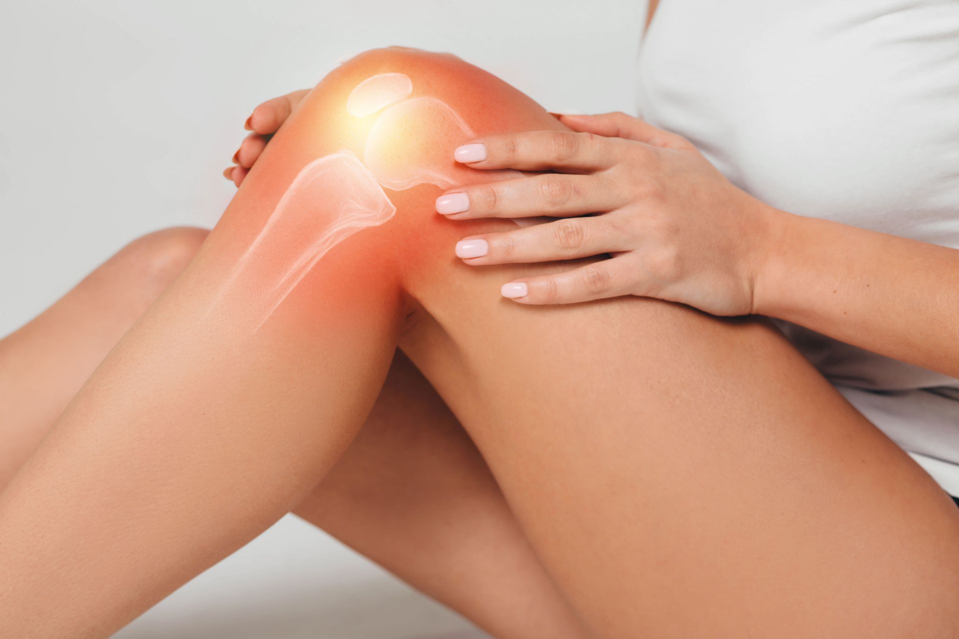 Woman holding knee in pain, highlighted with orange glow indicating pain and bones.