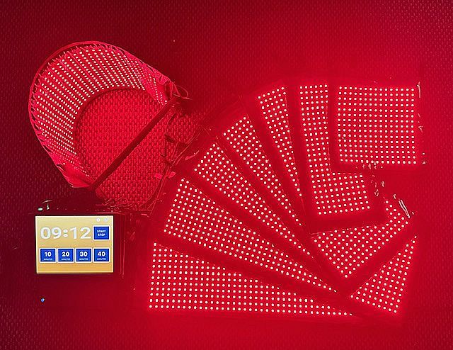 A person receiving body contouring treatment, with a technician using a handheld device on their abdomen, draped in a white towel.