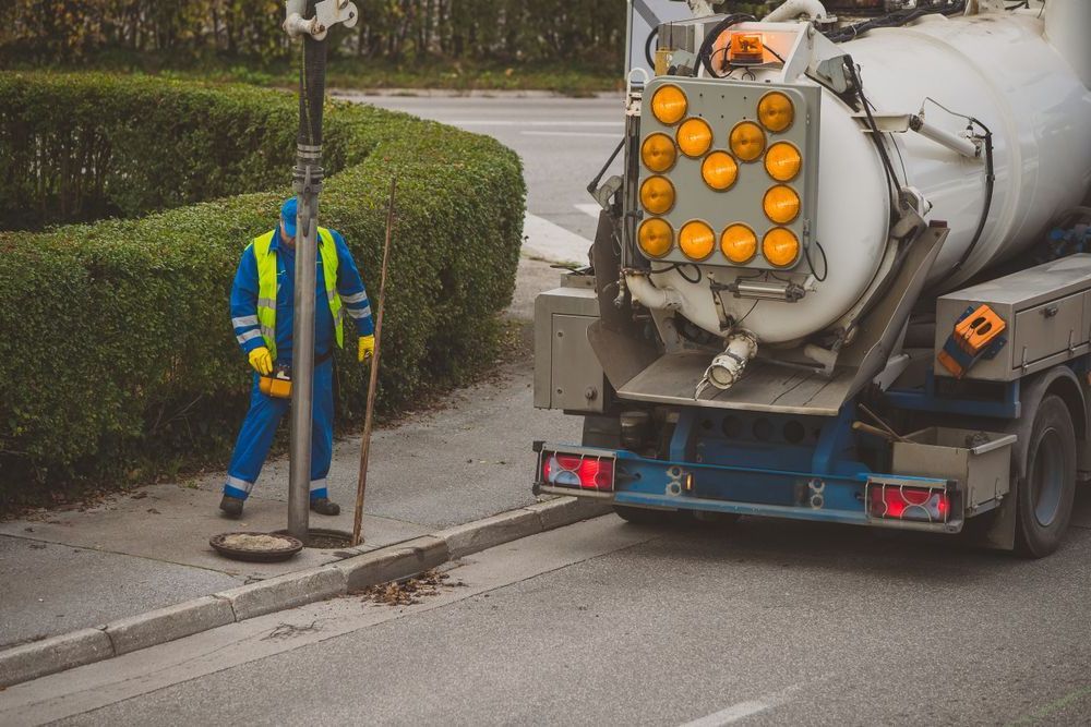 A Man Is Standing Next To A Vacuum Truck On The Side Of The Road — All Hours Vac Truck In Lakes Creek, QLD