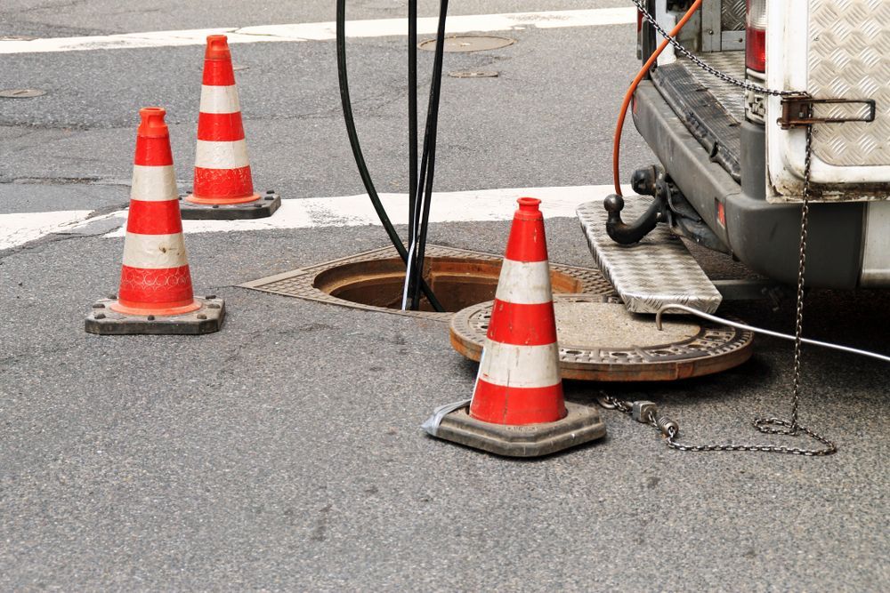 A Group Of Traffic Cones Are Sitting Next To A Manhole Cover — All Hours Vac Truck In Yeppoon, QLD